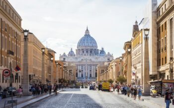 Blick auf die Via della Conciliazione mit dem Petersdom im Hintergrund, umgeben von historischen Gebäuden.